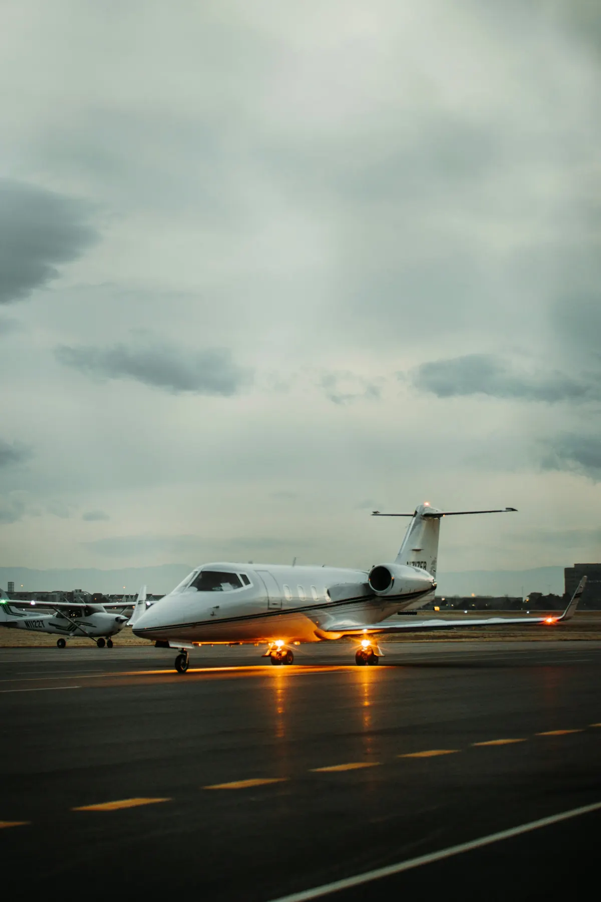 Light business jet taxiing at dusk with its landing lights on